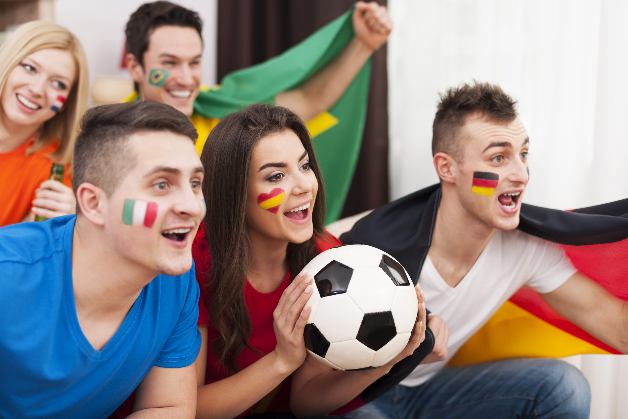 Multinational friends cheering football match at home